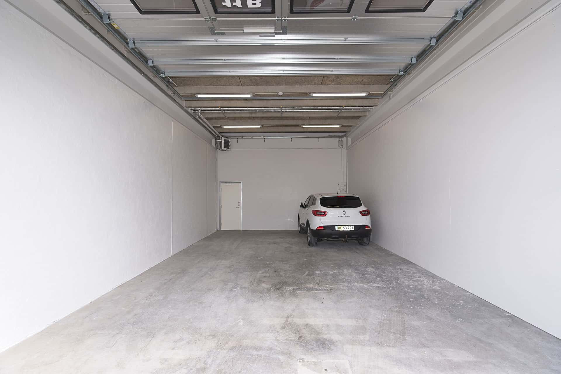 Rummeligt lagerlokale med en hvid bil parkeret